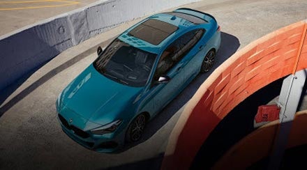 A blue metallic BMW 2 Series Gran Coupe driving down parking garage ramp.