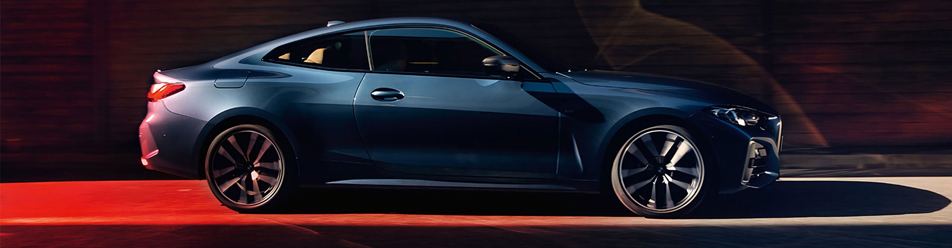 A blue BMW 4 Series Coupe driving down an alley.