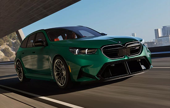 Green BMW M5 Touring driving on a city road. | BMW of Morristown in Morristown NJ