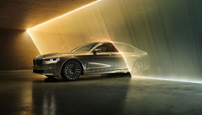 A BMW 7 Series driving through a sheet of falling water in a garage.