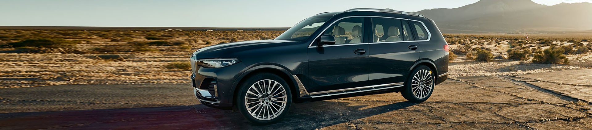 A BMW X7 parked along the road in a desert.