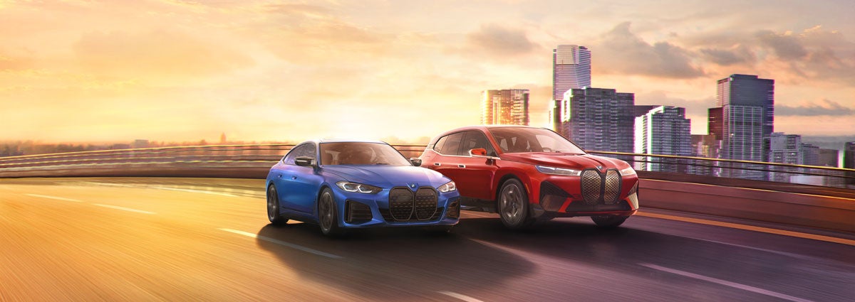 BMW iX and i4 driving down a city highway